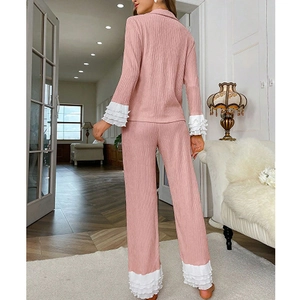Detailansicht der rosa Strick-Pyjamas mit weißen Rüschenmanschetten und elegantem Dekor