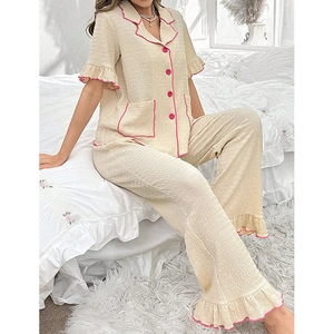 Women waffle knit short sleeve pajama set with pink piping and ruffle trim on white bed