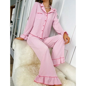 Women's pink two-piece pajama set featuring long-sleeved button-down top and ruffled trousers