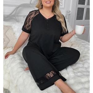 Detail view of black V-neck pajamas with delicate lace stitching on shoulders and leg hems