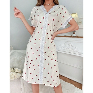 Dettaglio del pizzo a V e delle stampe a cuore rosso su camicia da notte estiva crema