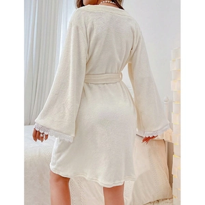 White coral fleece robe with lace cuffs and tie waist in a cozy bedroom setting