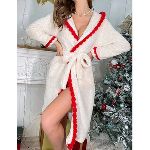 Detail of plush white flannel bathrobe with festive red pompom trim and soft texture