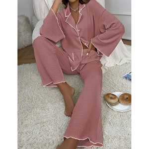 Détail d'un pyjama plissé rose avec passepoil blanc et boutons contrastés sur haut ample