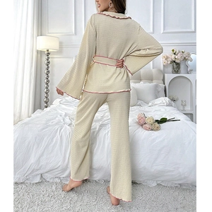 Women's cream loungewear set with pink ruffle trim and belted long sleeve top and pants