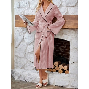 Pink ribbed robe detail showing contrast black trim and stylish ruffled cuffs near a fireplace