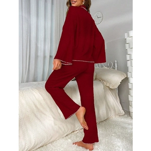 Ensemble pyjama bordeaux pour femme avec liserés blancs dans une chambre confortable