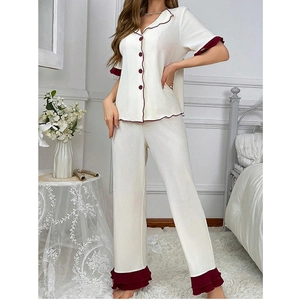 Detail of ruffle trim on cream pajama set with vertical ribbed texture and red buttons