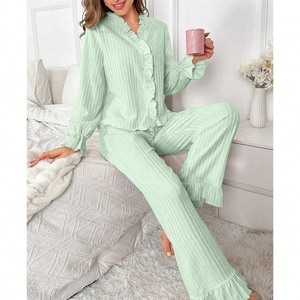 Detail of light green ruffled long-sleeve pajamas set with pearl buttons and textured fabric