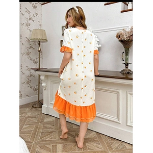 Détail d'une chemise de nuit fleurie avec ourlet à volants orange et motif floral