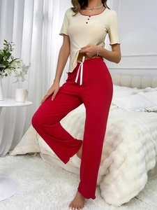 Détail du haut de pyjama côtelé beige avec bordure rouge et pantalon rouge assorti
