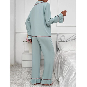 Pyjama chic en satin vert menthe avec liseré rouge et volants dans une chambre claire