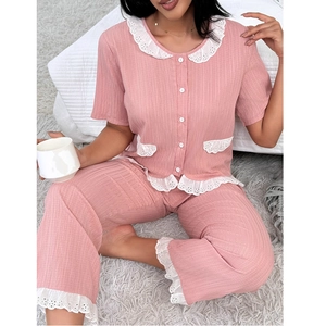 Détail de pyjama rose avec bordure en dentelle et texture verticale sur tapis gris