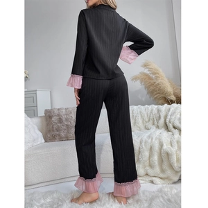 Women's black ruffled pajamas set with long sleeve top and pants in a home setting
