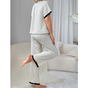 Completo pigiama in cotone bianco con balze e pizzo nero in ambiente domestico