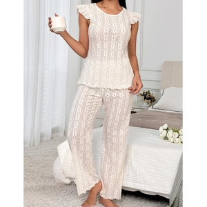 Detail of white two-piece pajama set with delicate floral eyelet lace and embroidery