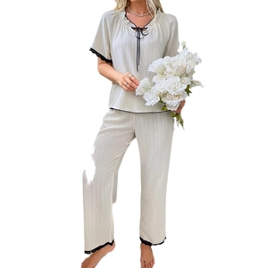 Elegante set pigiama bianco sporco con bordo in pizzo nero e fiocco decorativo