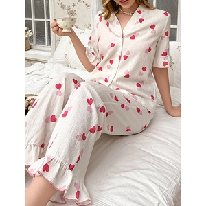 Women's pajama set with heart prints and flared sleeves in a cozy bedroom setting