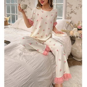 Detail of pink floral pajama set featuring ruffled cuffs and rose patterns on soft fabric