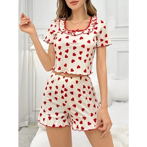 Close-up of heart print pajama set with ruffle trim and square neck detail on white fabric