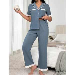 Blue knit pajama set with white lace trim and button-up shirt in a cozy bedroom setting