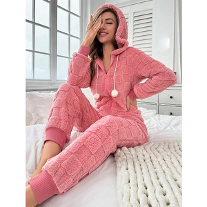 Detail of pink coral fleece jumpsuit showing textured checkerboard pattern and hooded pompom