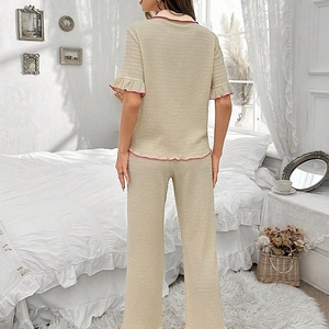 Detail of waffle knit pajamas set featuring pink lettuce trim on beige fabric