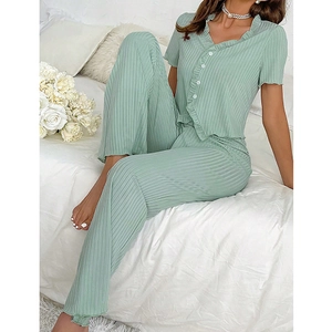 Close-up of light green ribbed fabric with ruffle edges and buttons on a V-neck pajama set