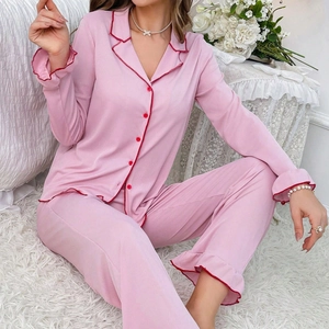 Detailed close-up of pink ribbed pajama set with red wavy scalloped edges and frilled hem