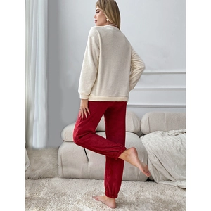 Women's heart coral fleece pajama set with cream top and red pants in cozy home setting
