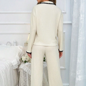 Detail of cream knit pajama set with scalloped black trim and textured fabric on back