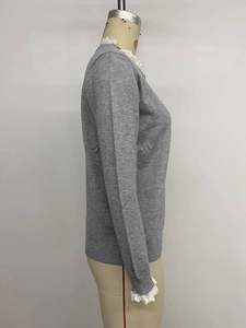 Detail of grey knitted sweater showing elegant white lace trim on sleeves and cuffs