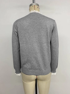 Detail view of the gray knitted sweater back with elegant white lace trim on the collar