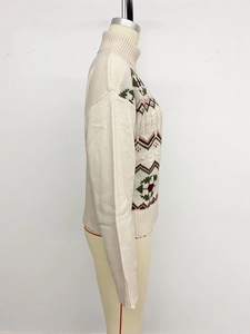 Close-up of geometric jacquard pattern on beige knit sweater with mock neck detail
