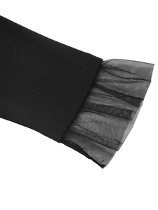 Detail of elegant black dress showing mesh patchwork sleeve cuffs with ruffled edges