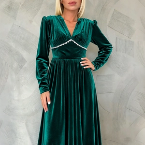 Macro detail of dark green velvet dress showing V-neckline and white wavy lace trim