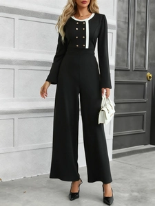 Detail of elegant black jumpsuit with white contrast collar and gold double-breasted buttons