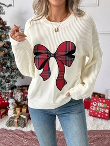 Detail of red plaid bow on white knit Christmas sweater with festive background