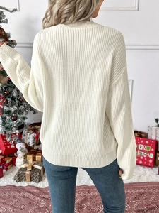 Detail of a creamy white crew neck knit sweater with vertical ribbing and a festive texture