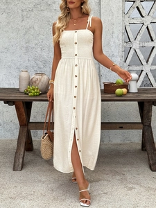 Detail of smocked bodice and brown buttons on a cream summer sundress with bow straps