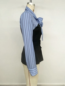 Detail of blue striped blouse featuring a large decorative bow and layered patchwork design