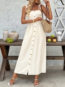 Detail of smocked bodice and decorative wood-style buttons on creamy white summer dress
