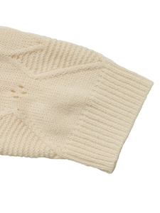 Detailed macro view showing the cable knit pattern and ribbed cuffs of the cream sweater