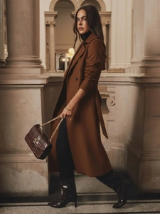 Dettaglio di un elegante cappotto di lana marrone scuro con cintura annodata e texture premium