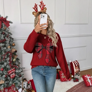 Close-up of a red knit Christmas sweater featuring a large plaid bow and soft texture