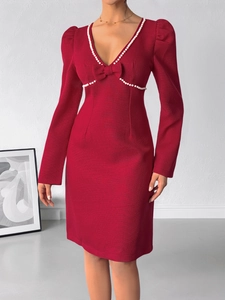 Détail de la robe rouge en maille avec col en V orné de perles et d'un nœud élégant