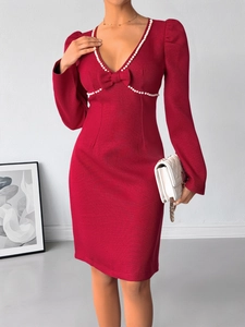 Détail du nœud orné de perles et décolleté en V sur une robe en tweed rouge