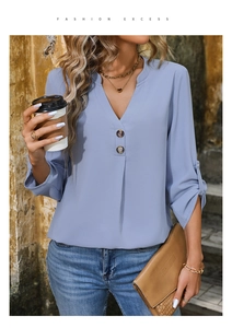 Close-up detail of V-neckline with wooden buttons and rolled sleeves on blue chiffon shirt