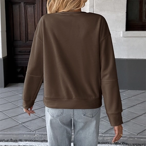 Back view of a loose dark brown crewneck sweatshirt styled with light blue denim jeans