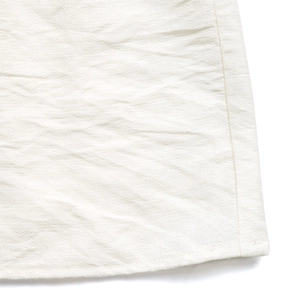 Dettaglio del tessuto plissettato bianco con cuciture fini e trama naturale
